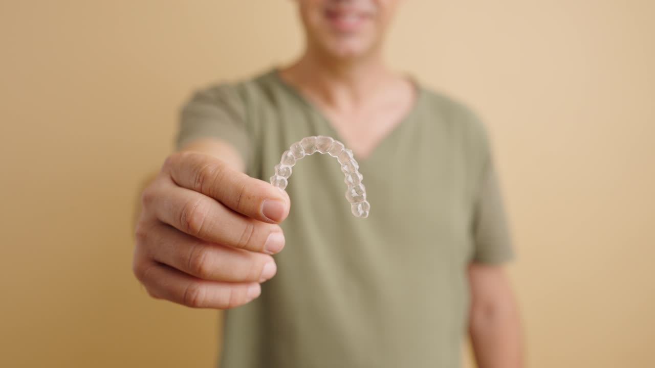 Man holding clear aligners for teeth straightening
