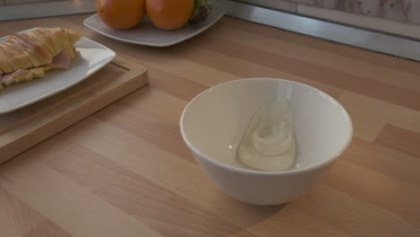 yogurt dropping in a bowl - croissant with ham in a plate on the side - slow motion