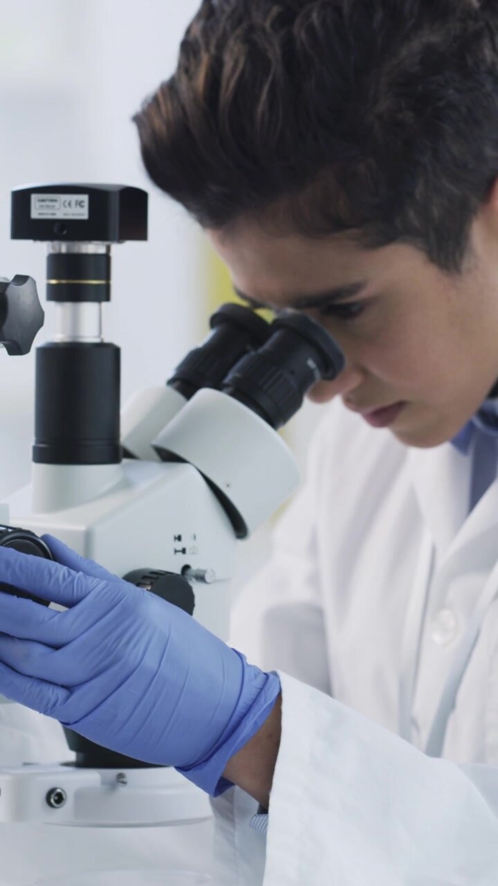 Scientist Examining Sample Under Microscope in Laboratory