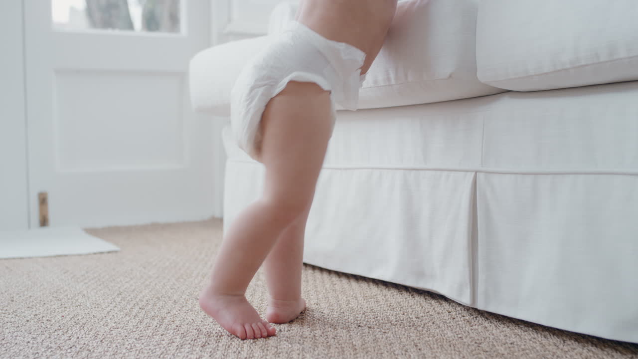 piernas de bebé aprendiendo a caminar niño pequeño dando sus primeros pasos usando pañal bebé lindo caminando en casa 4k