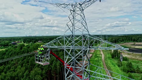 workers on boom lift during installation of overhead powerlines on transmission tower