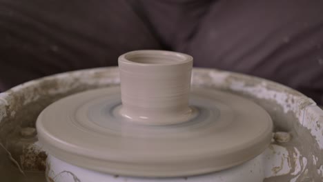 creative potter dexterity in shaping wet claypot on fast rotating wheel close up