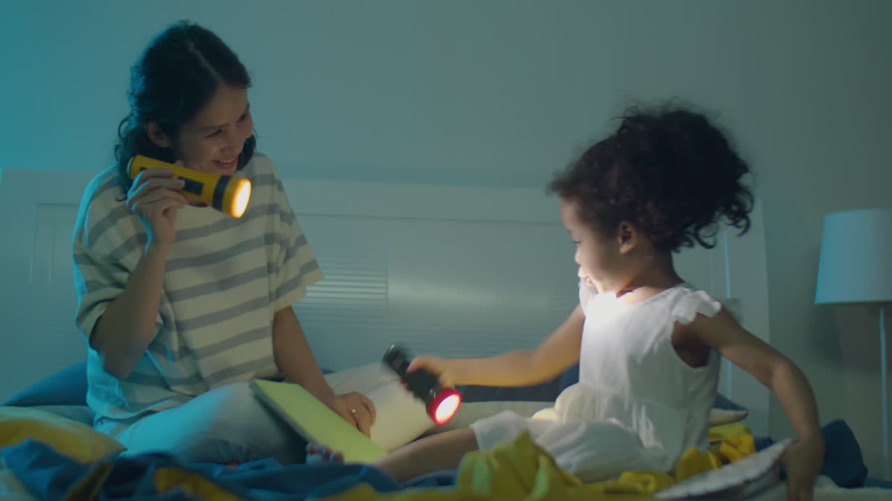 Little Girl and Mom Playing with Flashlights on Bed