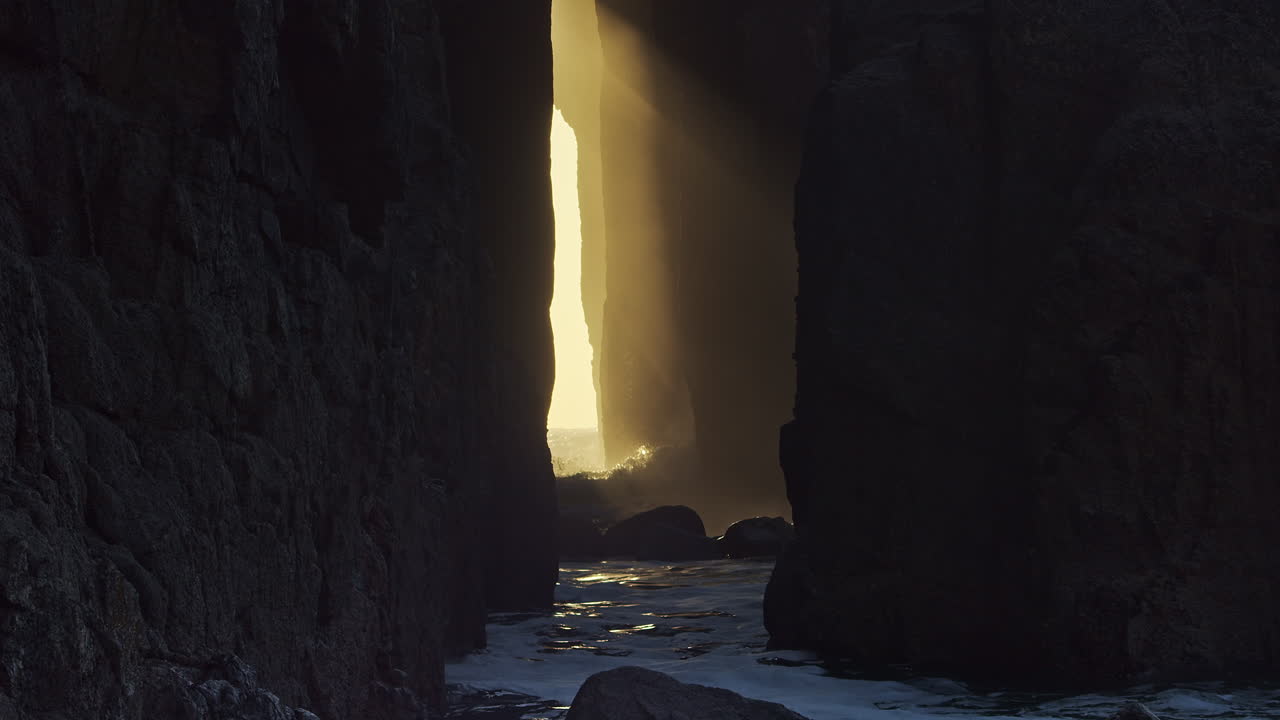 Havbølger slår mod klippebuen Zawn Pyg på Nanjizal Strand, Cornwall, Storbritannien