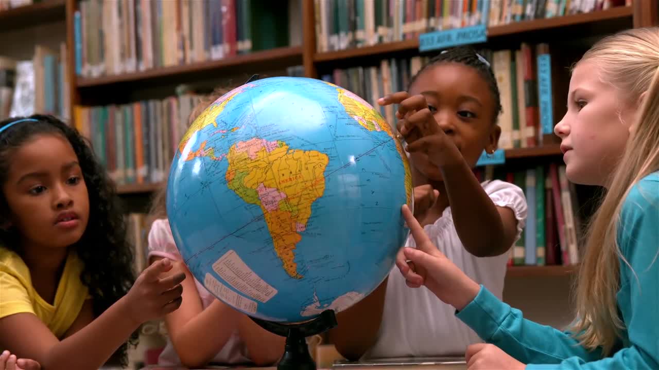 Graziose bambine che guardano un mappamondo in biblioteca