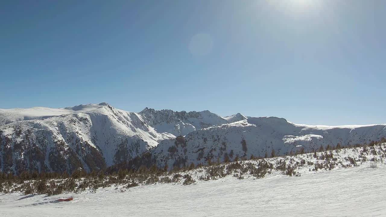 Pista de esquí y horizonte de montañas cubiertas de nieve