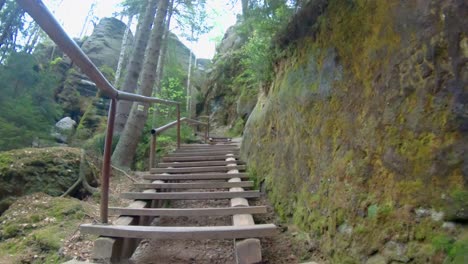 walking up wooden stairs in between rocks in national park adršpach