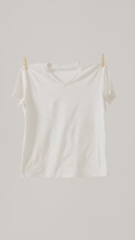vertical video of close up of white t shirt hanging on white background with copy space