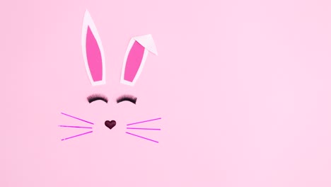 monochrome easter bunny blinking with eye lashes on pastel pink background. minimal flat lay stop motion