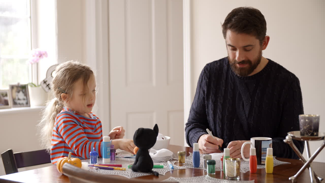 padre e hija haciendo máscaras de halloween en casa juntos