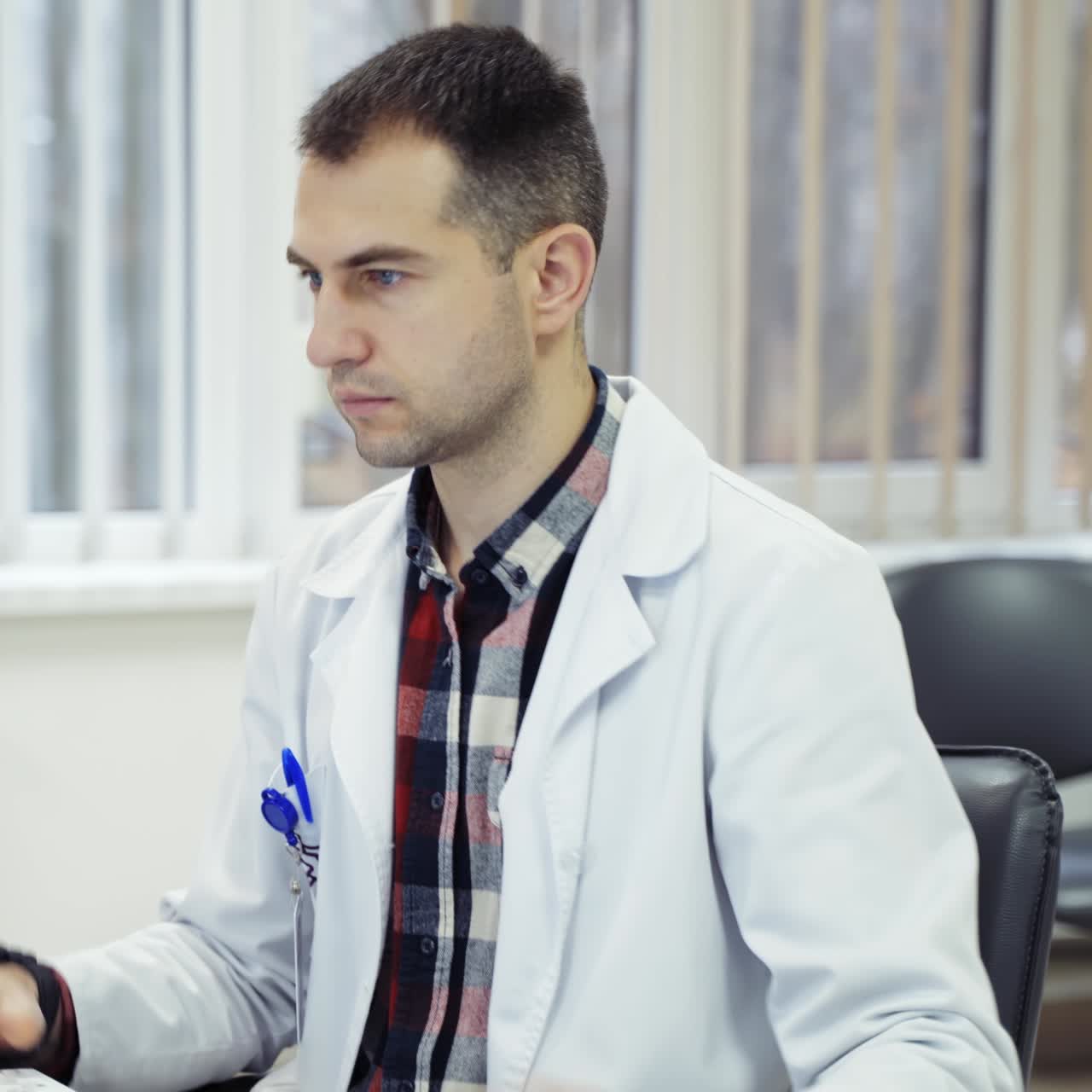 Male doctor in lab coat at desk. Medical specialist working on a computer in medical office. Tired doctor in front of a monitor.