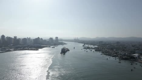 big ship sailing into city harbor, sunny day, aerial dolly in