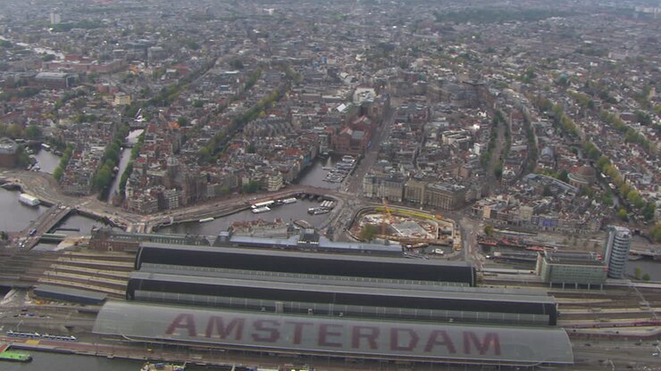 Aerial establishing shot of Amsterdam Central Station with the city center behind