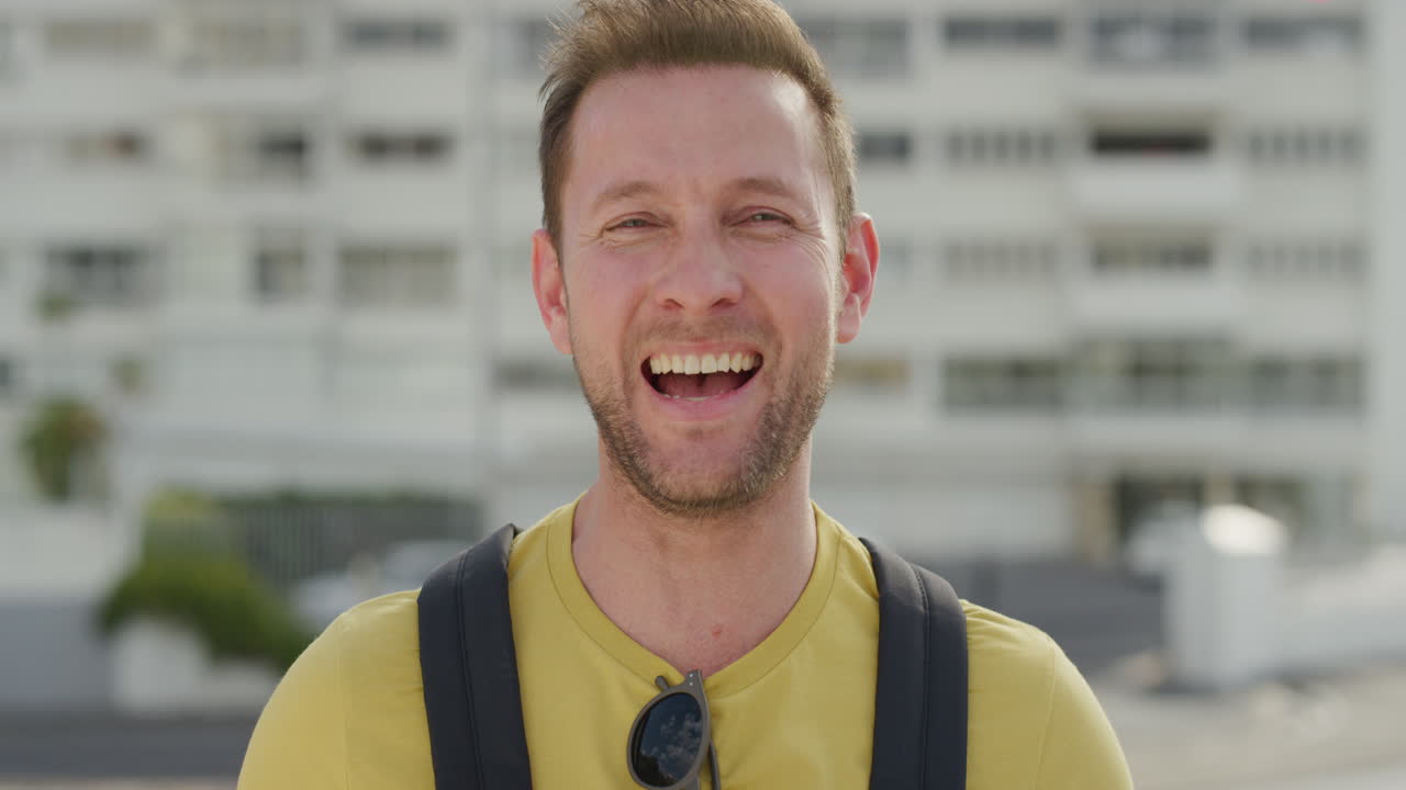 초상화 매력적인 백인 남자가 웃으며 편안한 생활 방식을 즐기고 행복하고 독립적인 남자가 도시에서 따뜻한 여름 날을 즐기고 있습니다.