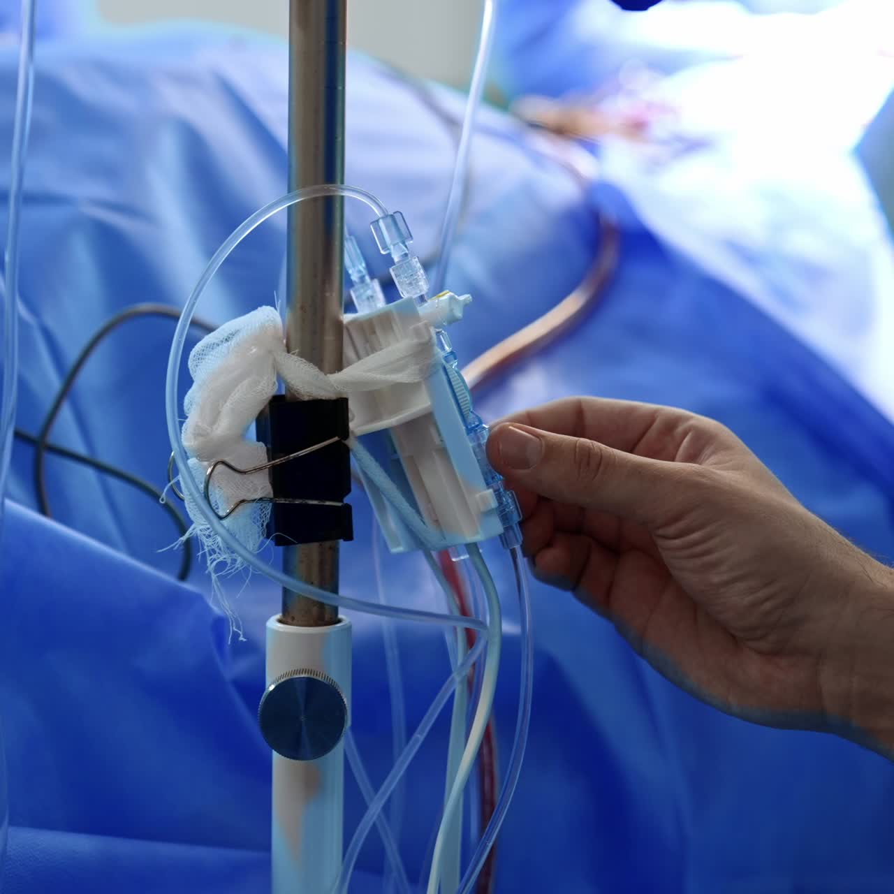 Male hand checking the drop counter equipment during operation. Anesthesiologist working in the surgical room