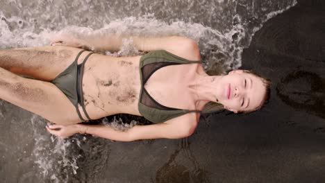 slow motion: bikini model on the beach getting washes away by a wave