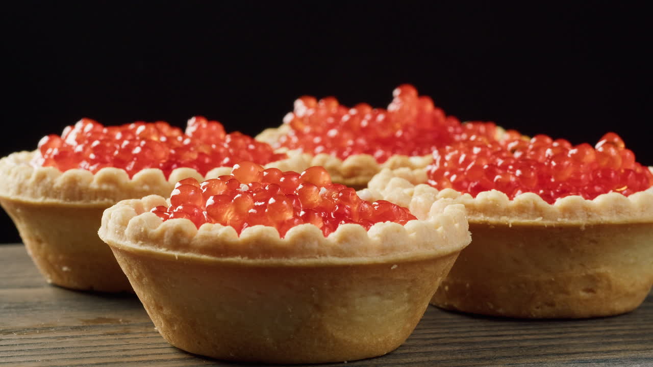 Cucchiaio d'oro che aggiunge caviale rosso a deliziose tartellette
