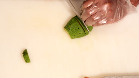 chef slicing thinly the green avocado for sushi rolls