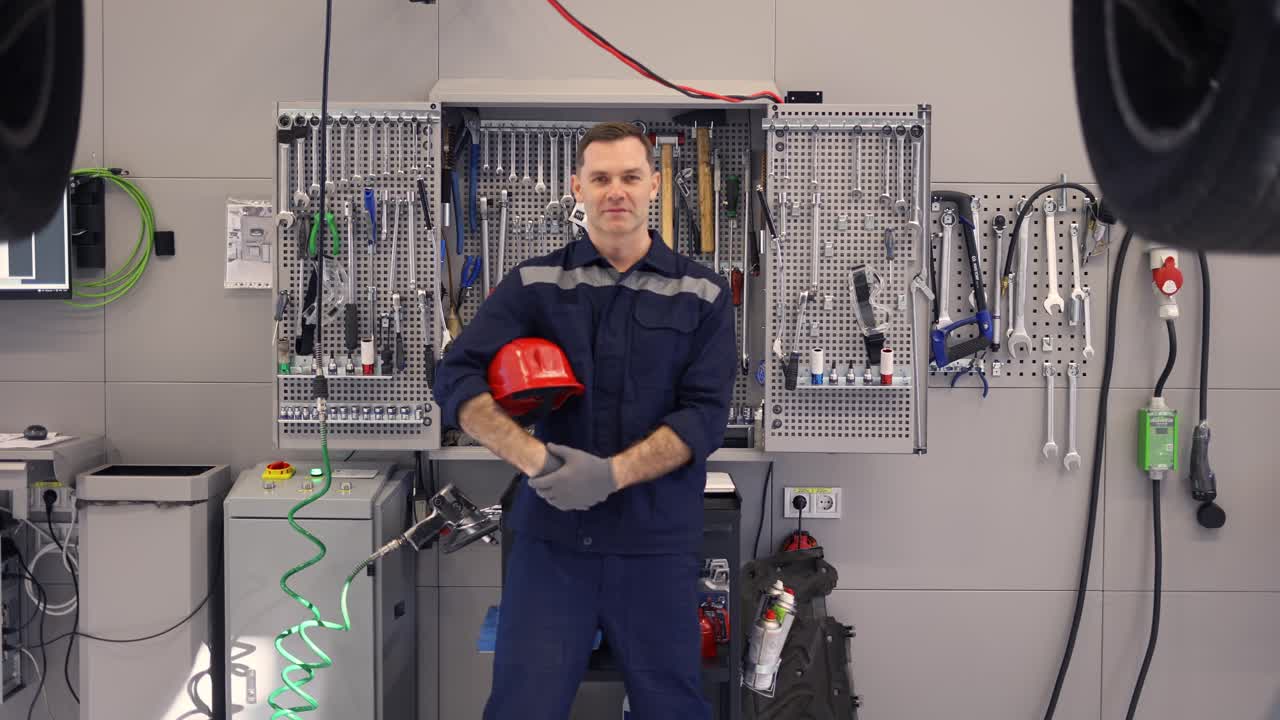 Full length of a car mechanic in a car workshop with equipment on the background