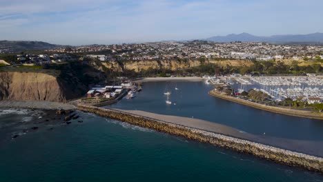 sweeping panoramic view of luxury ocean side homes, jetty, and boat harbor