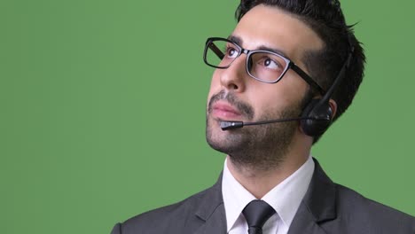 young handsome bearded persian businessman against green background