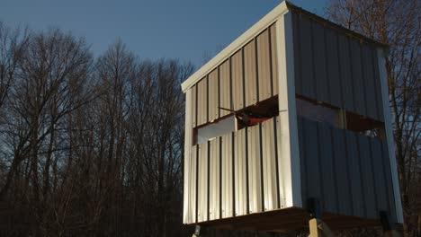 hunter aims hunting rifle out of deer blind