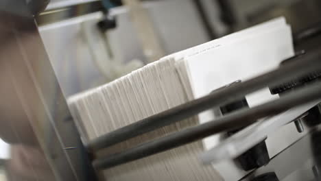 close up of the printing machine, man's hand puting a stack of paper inside of the machine, machine presses the stack together