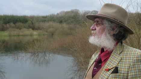 an elderly man looking out over the lake sadly