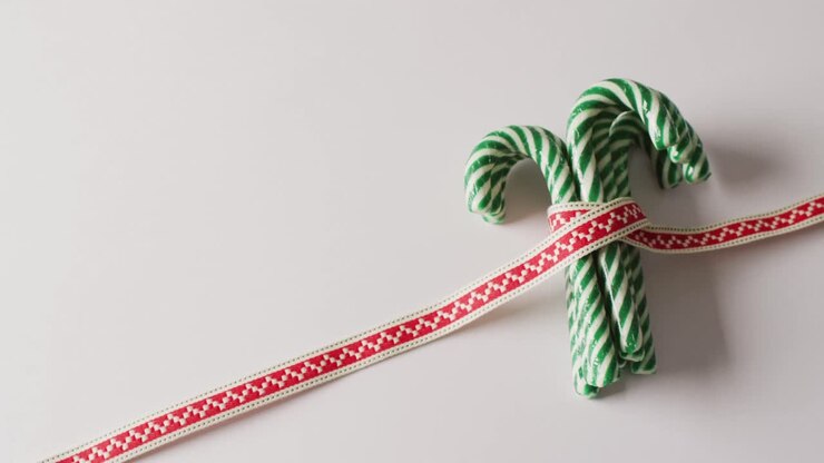 Video of green christmas canes with ribbon over white background