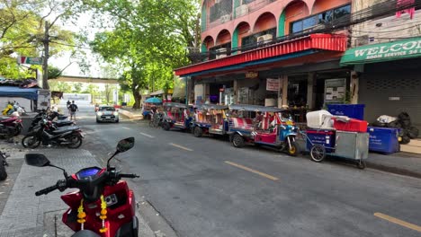 motorbikes and taxis move along a busy urban street.