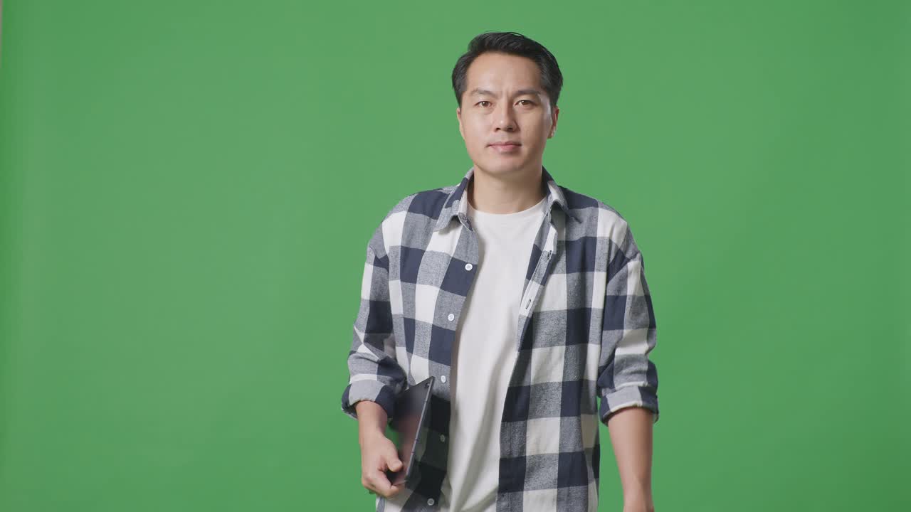 스튜디오에서 녹색 스크린에서 는 동안 태블릿을 들고 있는 아시아인