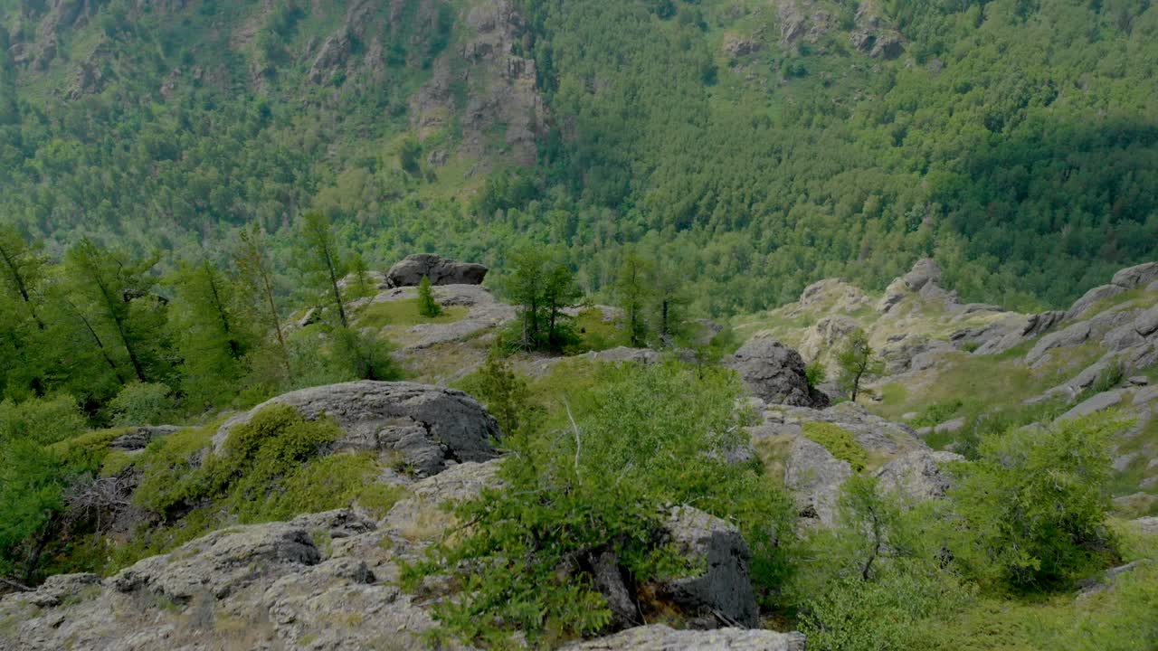 vista aérea, el avión no tripulado vuela sobre la chica sentada en una pared del acantilado