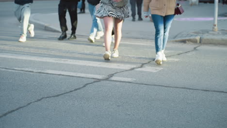 a city view showcasing a black car parked on the side of the road with people walking across the street