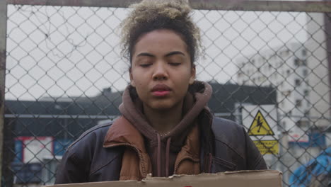 Close-Up-View-Of-Young-American-Female-Activist-Holding-A-Cardboard-Placard-Against-The-Use-Of-Plastics-During-A-Climate-Change-Protest-While-Looking-At-Camera