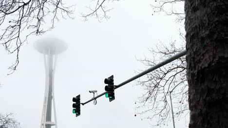cloudy overcast shot of the futuristic space needle skyscraper observation tower -  it is a city landmark and is considered an icon of seattle - surveillance camera on street lights