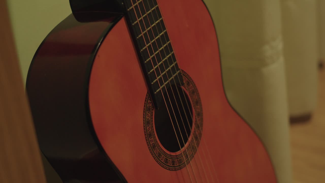 Primer plano del cuerpo de una guitarra acústica española apoyada en una pared amarilla