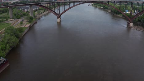 Aerial-tilting-up-shot-from-the-Mississippi-River-to-reveal-High-Bridge-with-downtown-Saint-Paul,-Minnesota-in-the-distance