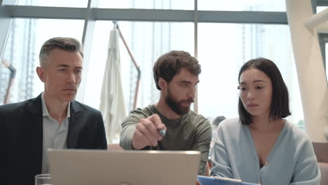 a work team discusses details of some reports on the laptop in a coffee shop