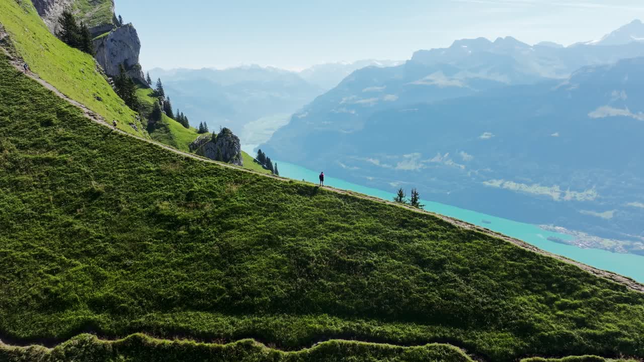 Hiker explores green mountain ridge with expansive lake views in the Swiss Alps