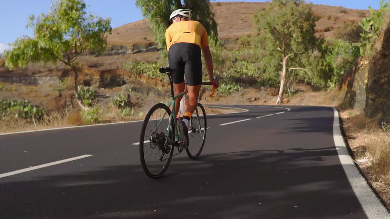On a peaceful morning, a man rides his road bike for outdoor exercise on a road with no traffic. The slow-motion video captures the essence of extreme sports
