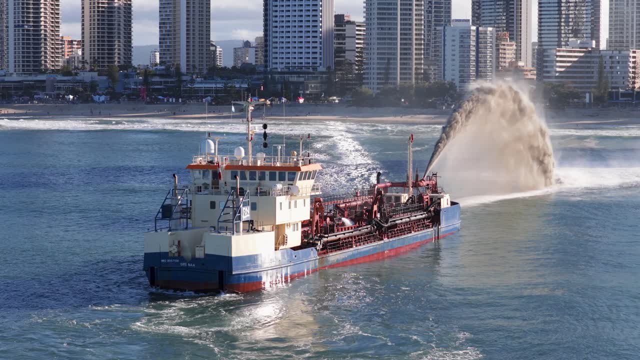 Aerial view of a dredging ship pumping sand in Gold Coast waters, with city skyline in the background during sunset