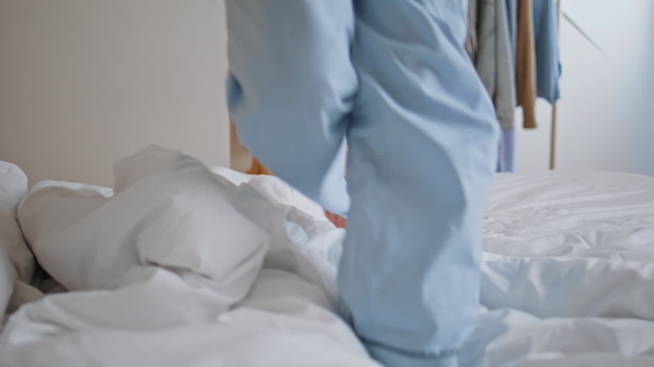 Pyjamas legs jumping bedroom sunlight closeup. Energetic woman listening music