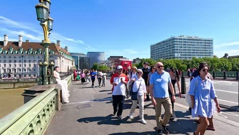 crowds walk across bridge near ferris wheel