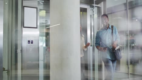 Video of happy diverse woman and man walking and talking in office
