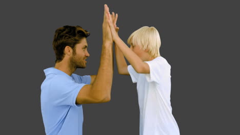 hombre dando un alto cinco a su hijo en fondo gris