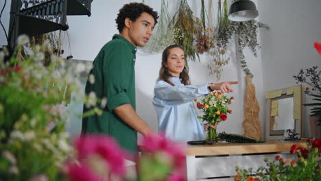 el hombre africano disfruta de la tienda de flores en verano. la chica florista atractiva trabaja en el negocio.