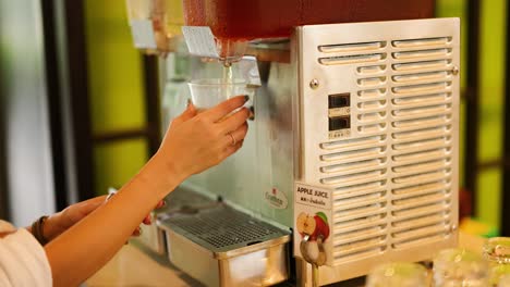 person using machine to pour apple juice