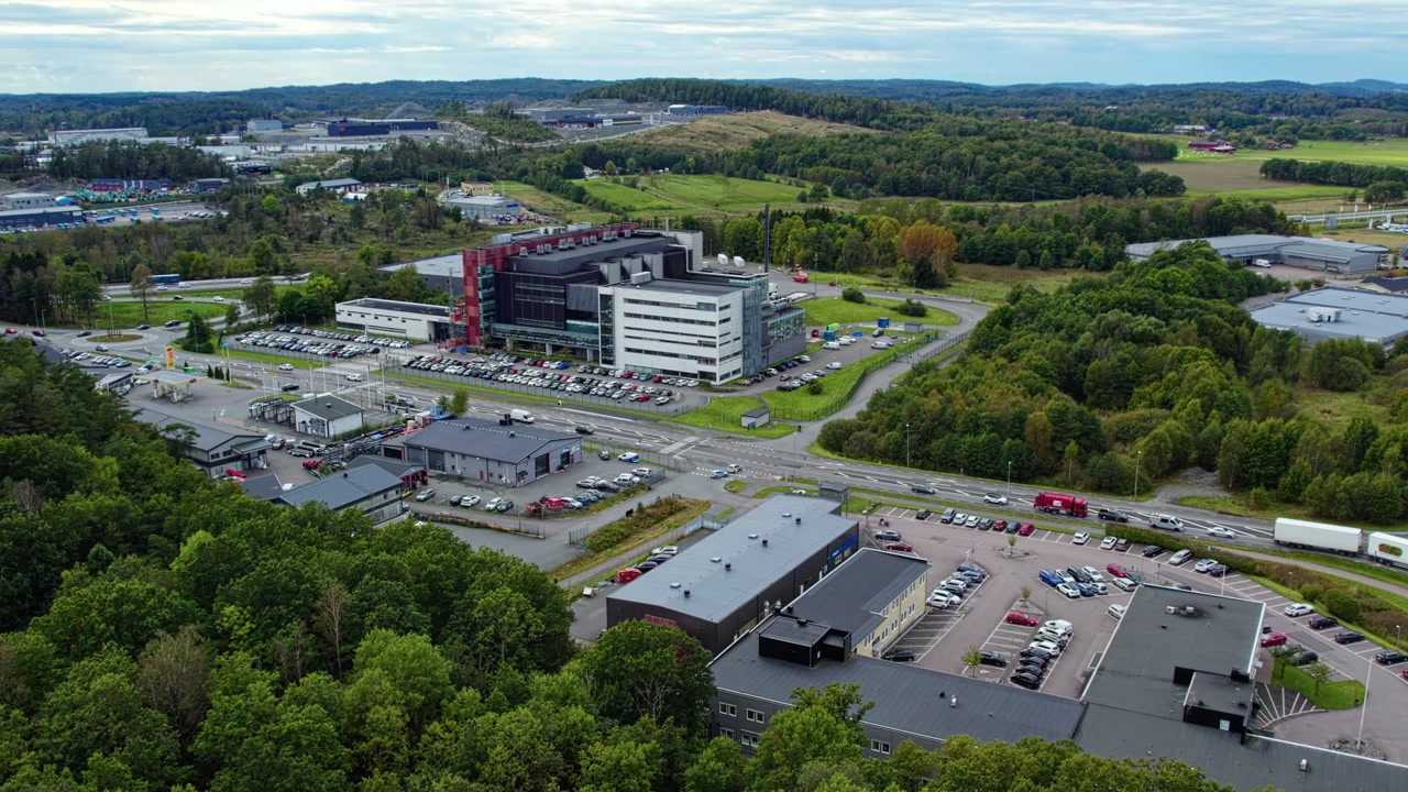 Aerial drone view shows Swedish Match factory in Kungalv with production buildings parking areas vehicles road network and green surroundings in suburban landscape