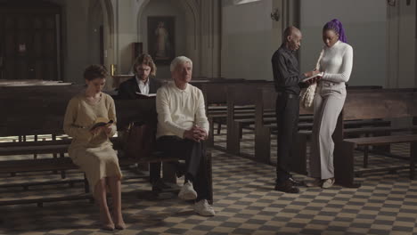parishioners praying while african priest talking to woman