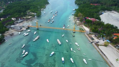 imágenes aéreas de drones en 4k: scooters cruzando el icónico y pintoresco puente amarillo que conecta las islas nusa lembongan y nusa ceningan en bali